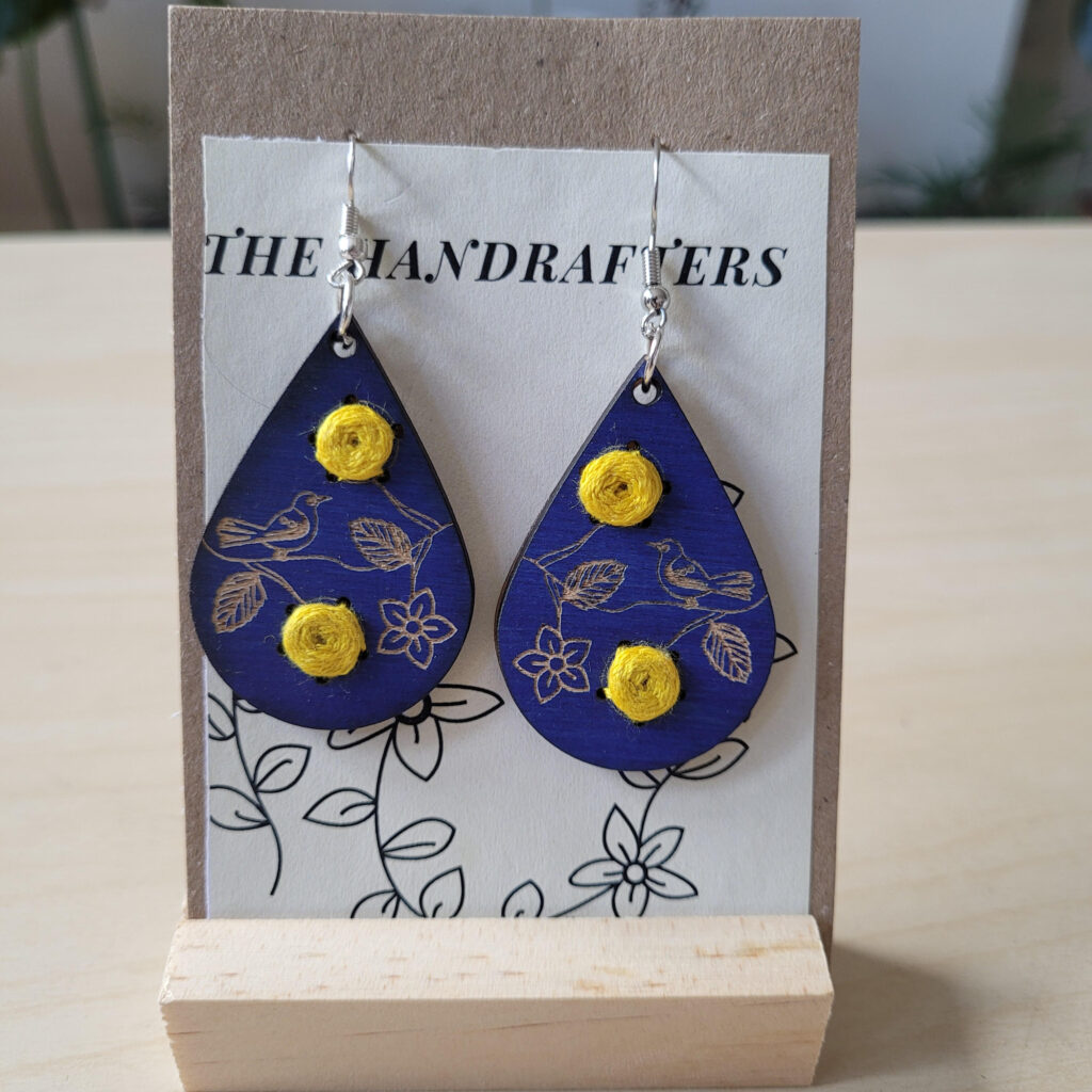 Teardrop shaped blue earrings with engraved birds and embroidered yellow flowers